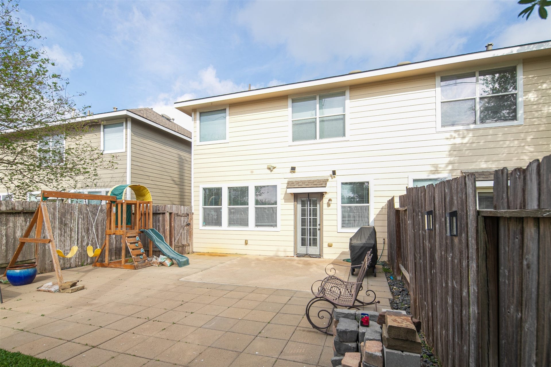 This spacious backyard features a large patio perfect for entertaining and a playset for family fun. Enjoy outdoor living in a private, fenced setting.