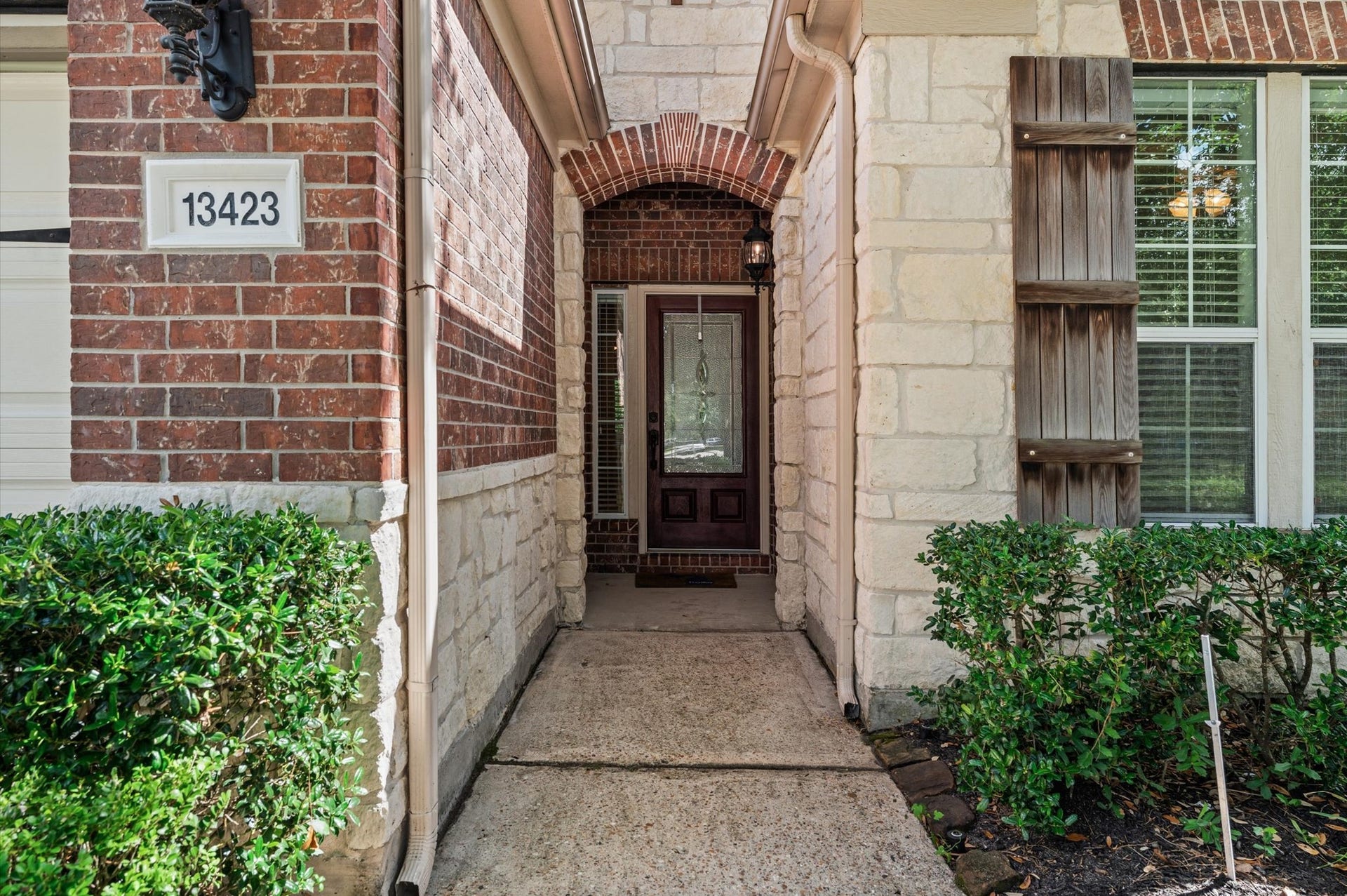 13423 Hartland Lake Lane, Houston, TX 77044 Charming entryway with a blend of brick and stone accents, featuring a stylish front door and lush greenery for welcoming curb appeal.