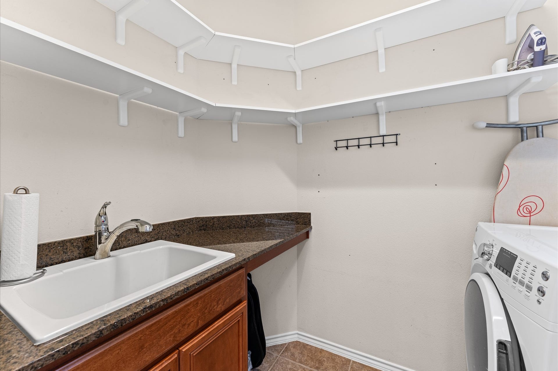 13423 Hartland Lake Lane, Houston, TX 77044 Efficient laundry room featuring ample shelving, a deep sink with a faucet, and a convenient countertop for folding and organizing.