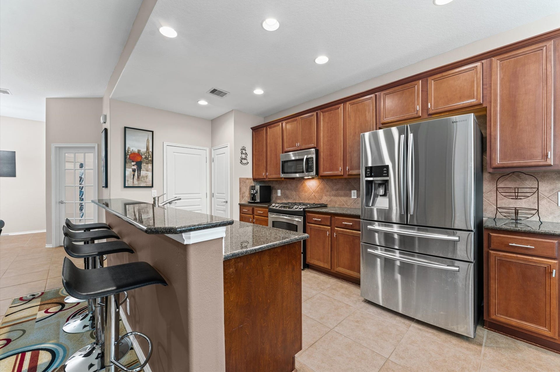 13423 Hartland Lake Lane, Houston, TX 77044 Modern kitchen with sleek stainless steel appliances, wood cabinetry, and a spacious granite countertop breakfast bar with stylish seating.