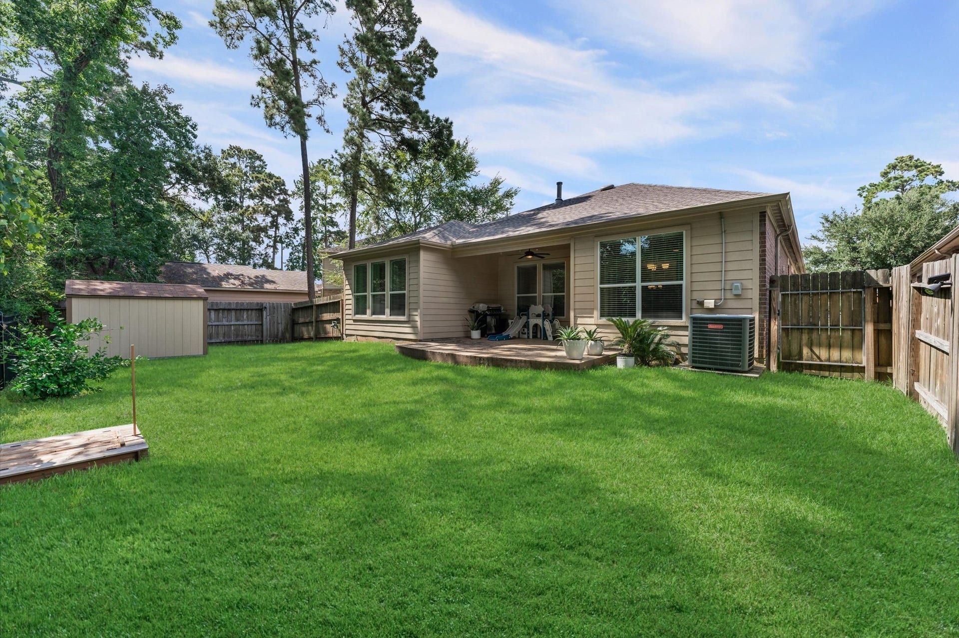 13423 Hartland Lake Lane, Houston, TX 77044 Spacious backyard featuring a well-maintained lawn, a cozy covered patio, and a storage shed, perfect for outdoor relaxation and activities.