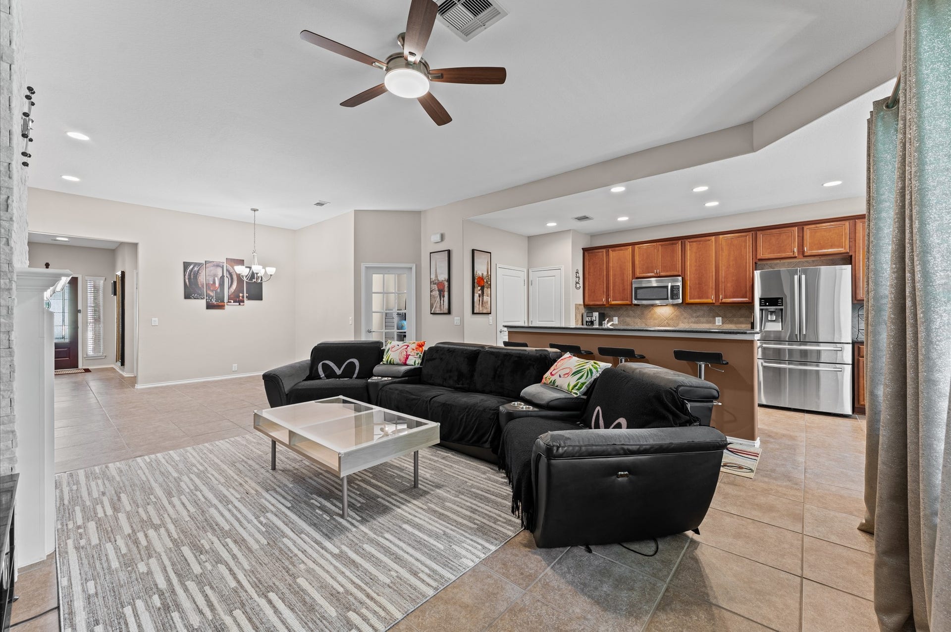 13423 Hartland Lake Lane, Houston, TX 77044 Spacious open-concept living area features a modern kitchen with stainless steel appliances and wood cabinetry, seamlessly flowing into a cozy space with a sleek ceiling fan and ample natural light.
