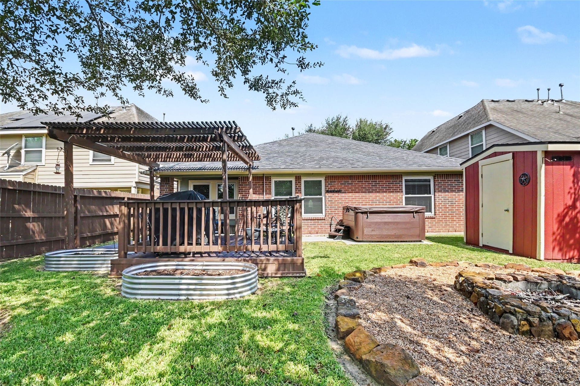 213 Rippling Creek Lane, Alvin, TX 77511 This backyard is your own private playground, you have some raised garden beds, a hot tub, deck and a firepit