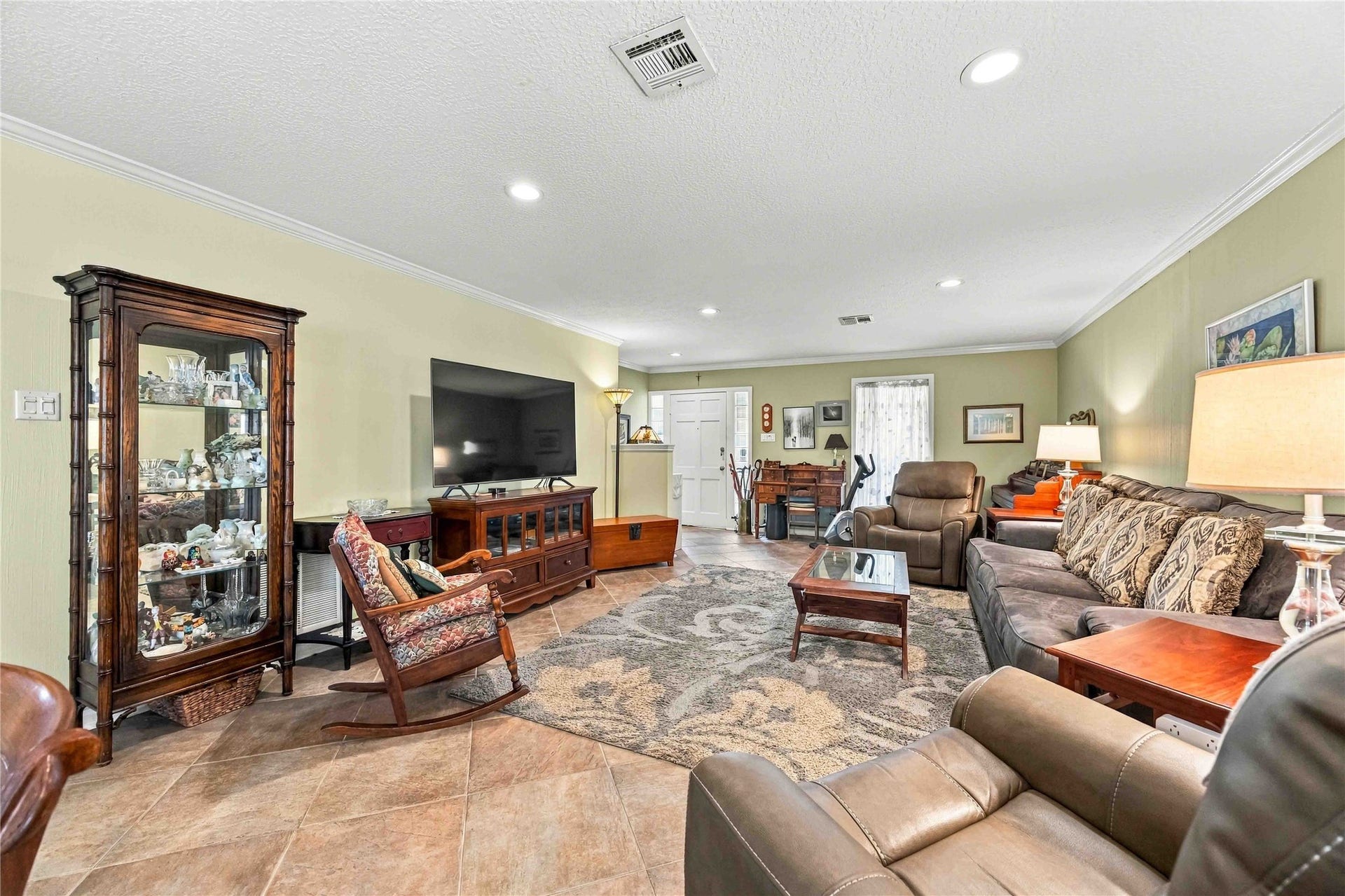 Another view of the living room featuring recessed lighting, crown molding, and a large front window.