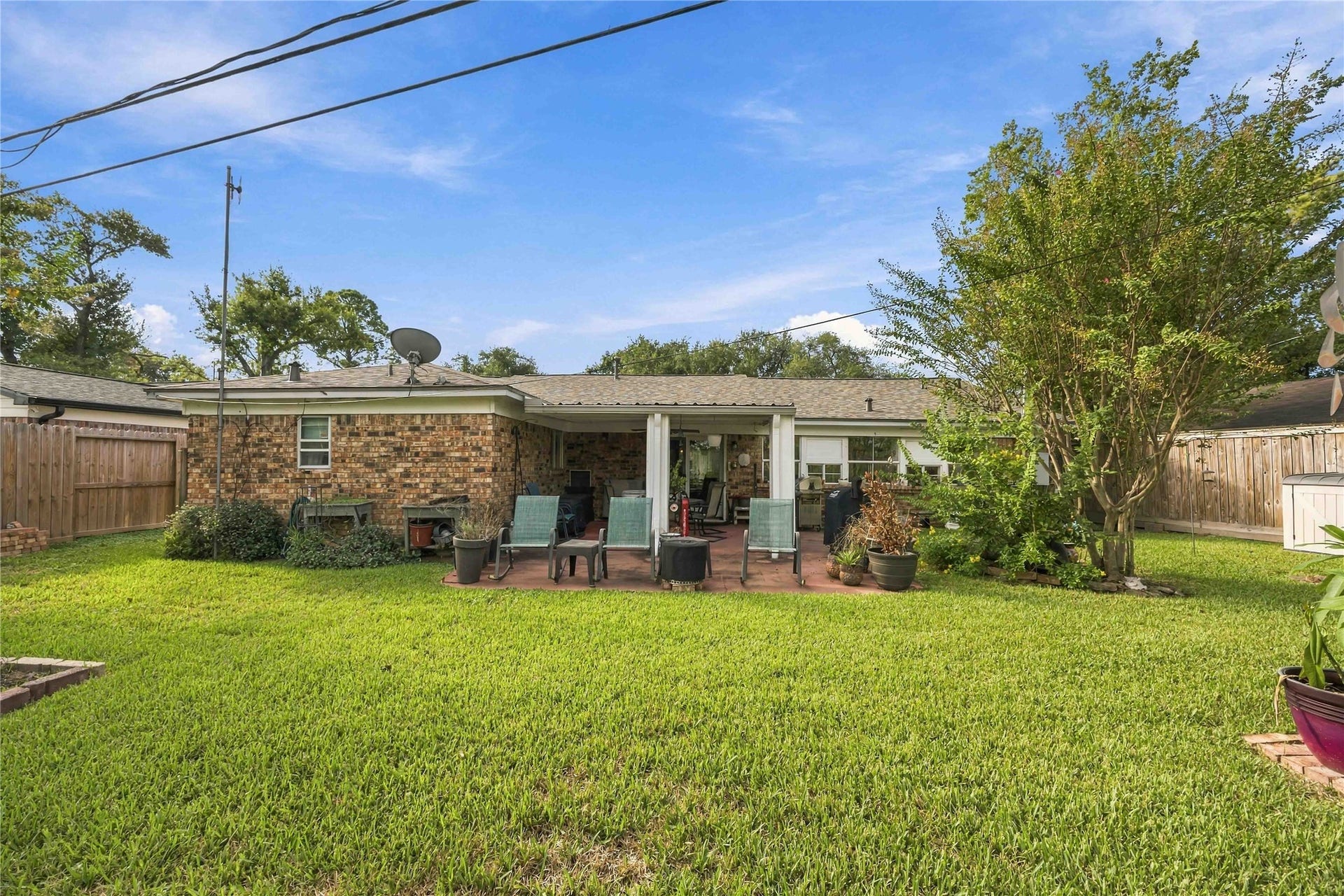 Looking back toward the home, the full brick exterior and covered patio complete the backyard setting.