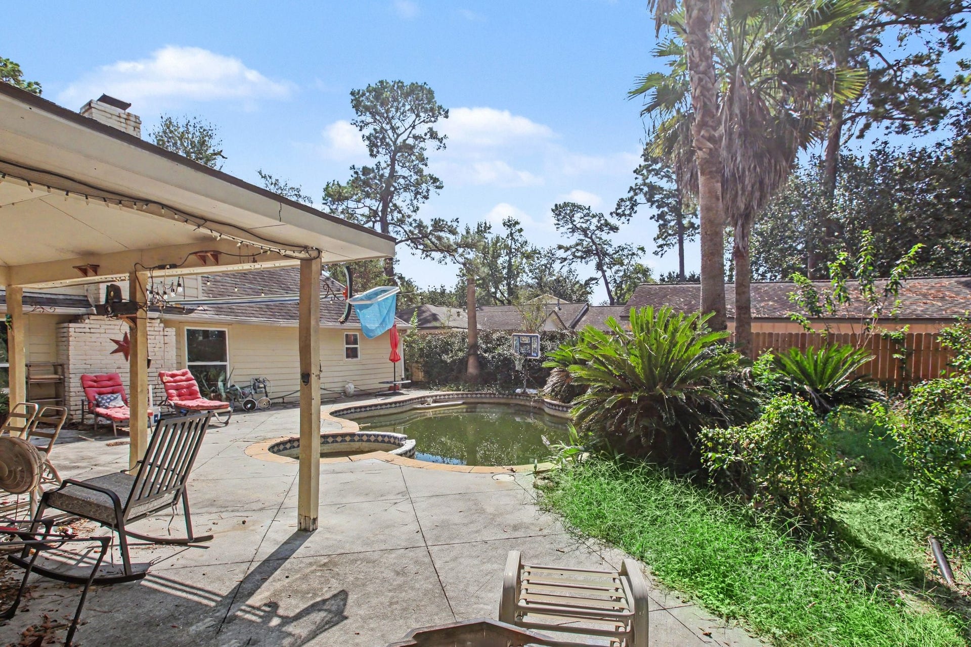 Mature palm trees, a covered patio, and the pool offer great potential
