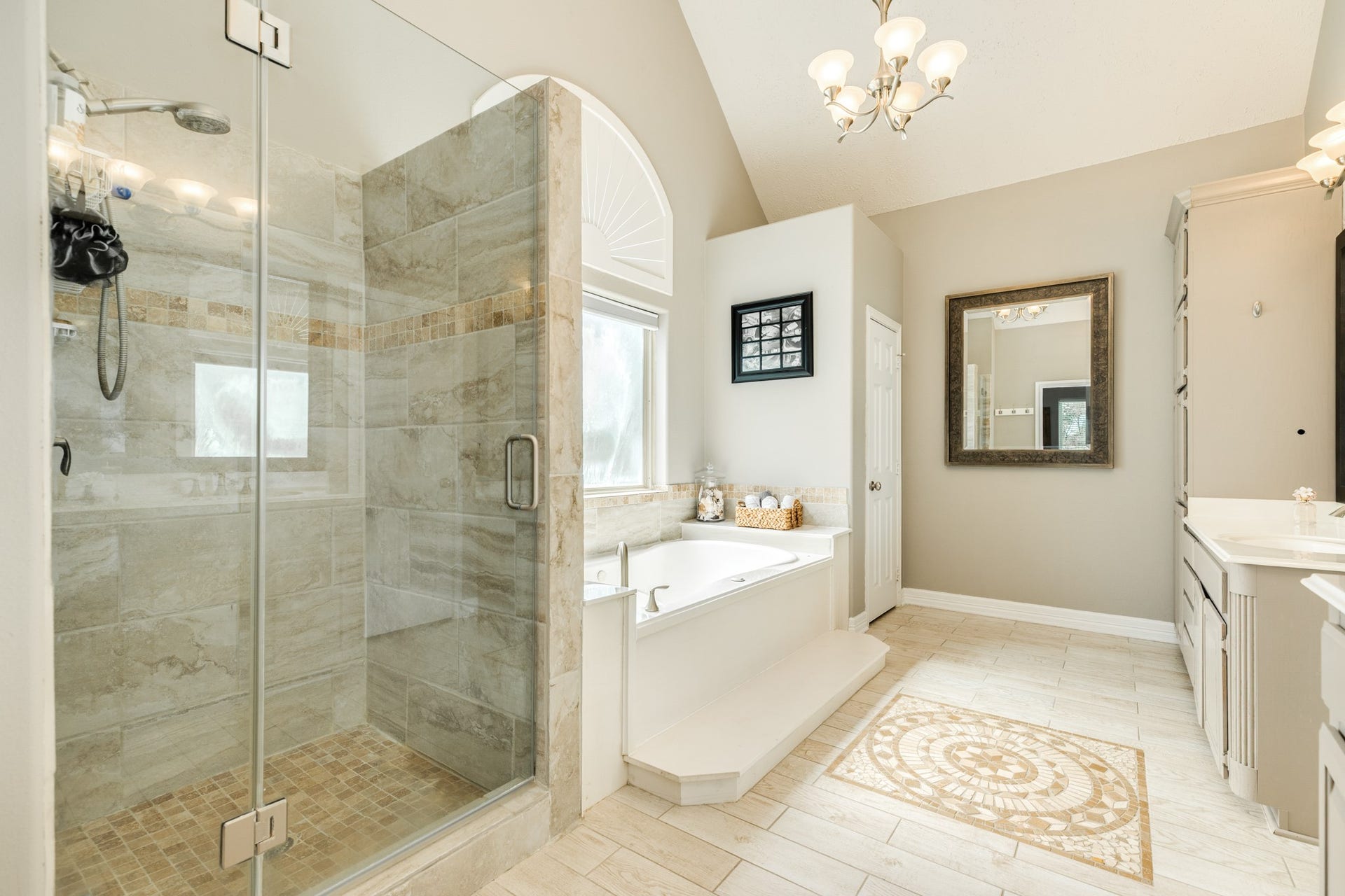 16337 County Road 171, Danbury, TX 77534 Another view of the en suite primary bath, showcasing the oversized glass-enclosed walk-in shower and soaking tub beneath a beautiful arched window.