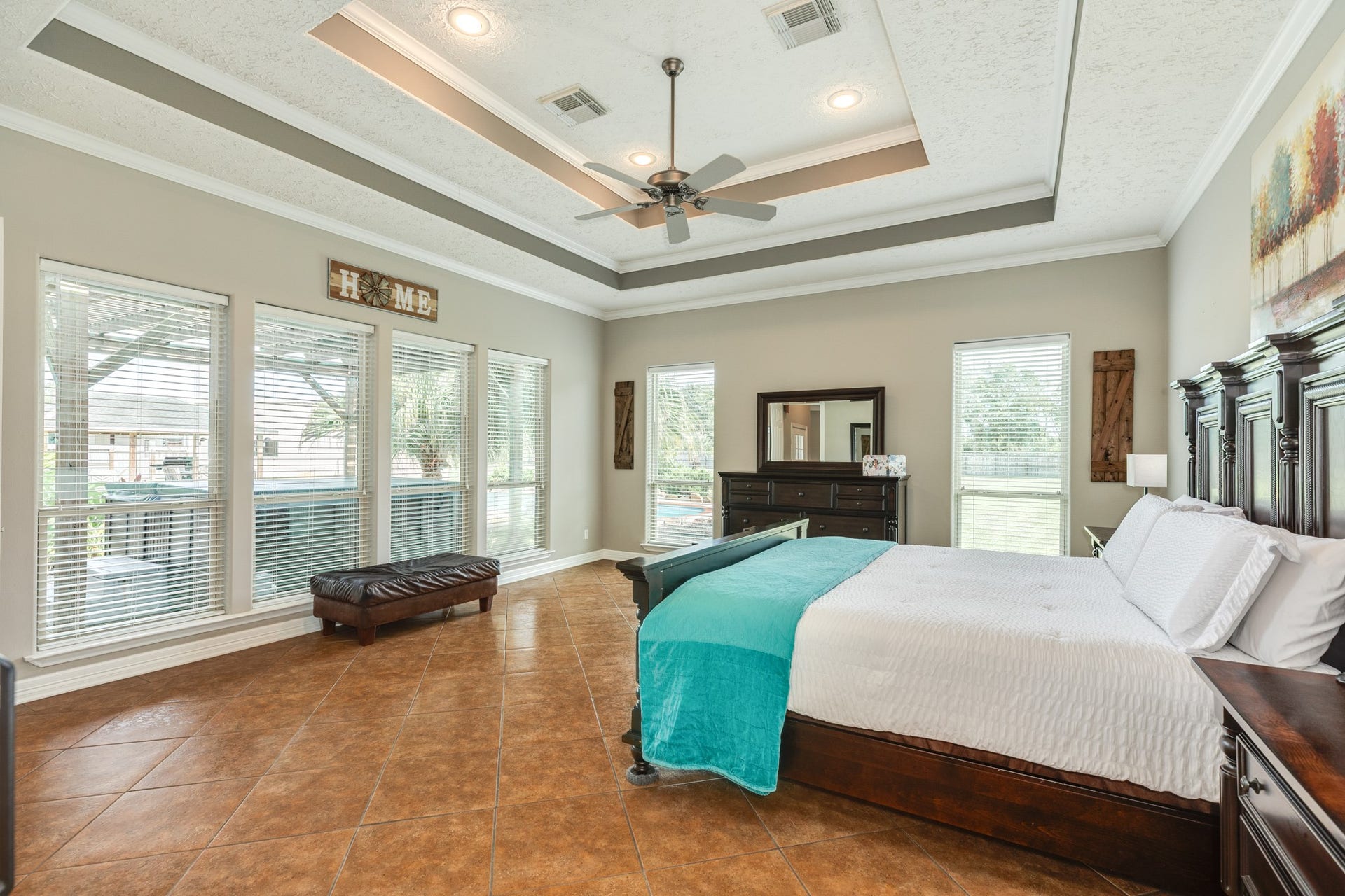 16337 County Road 171, Danbury, TX 77534 The primary suite offers a generous retreat with an impressive tray ceiling, crown molding, and a wall of windows overlooking the backyard and hot tub.