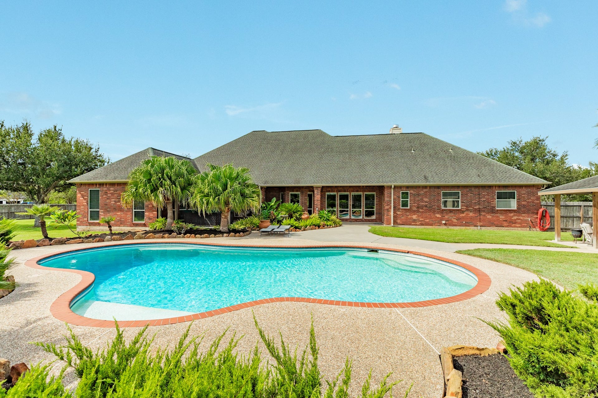 16337 County Road 171, Danbury, TX 77534 The backyard centers around a large saltwater pool with a Caretaker automatic cleaning system, surrounded by extensive landscaping and oversized flower beds for a resort-like setting.