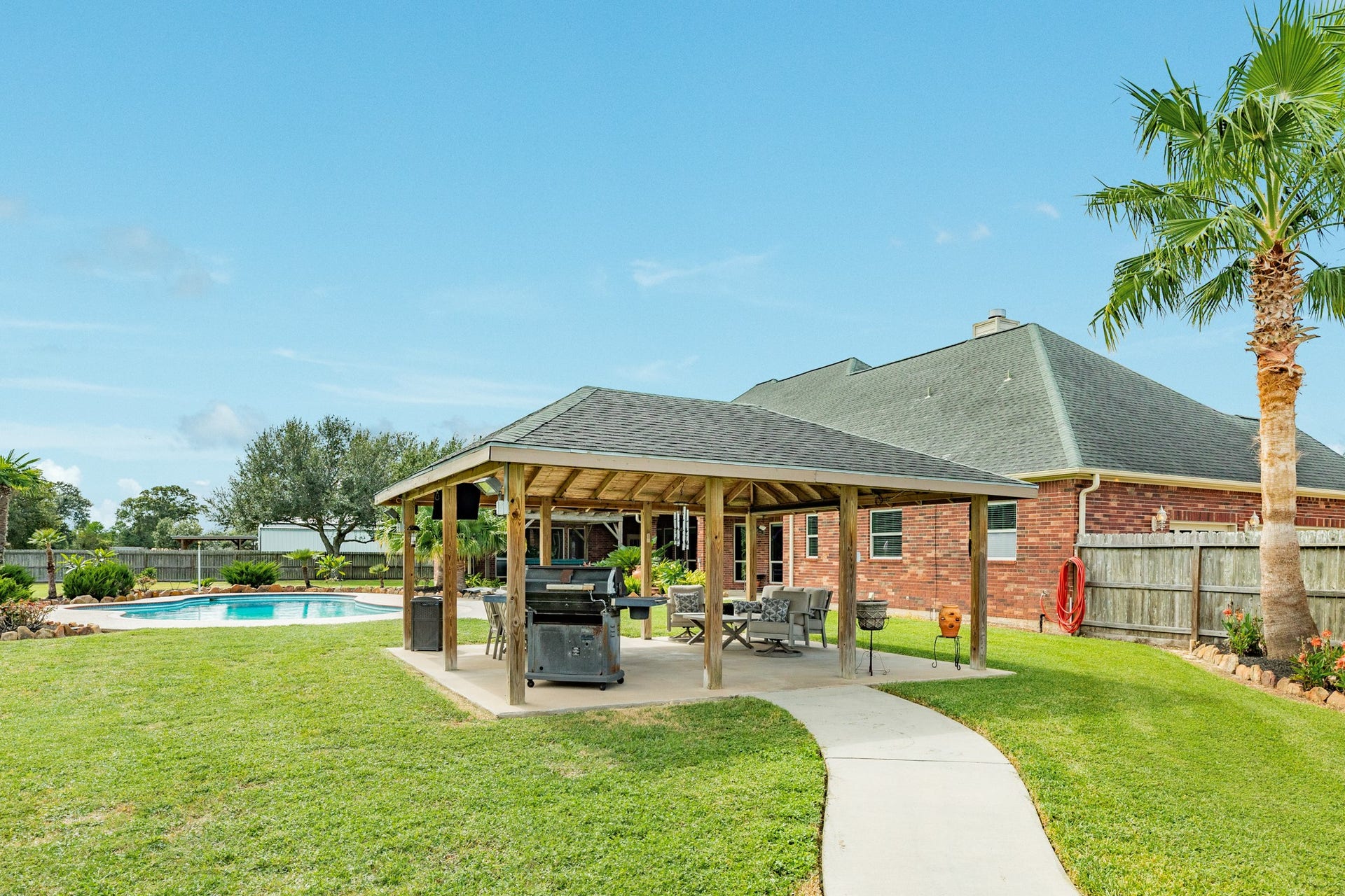 16337 County Road 171, Danbury, TX 77534 Designed for effortless outdoor entertaining, this covered outdoor kitchen and living area features a TV setup and overlooks the pool and spacious backyard. The perfect spot for hosting or relaxing.
