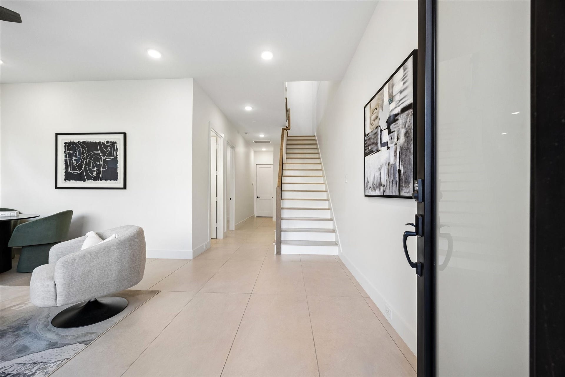 A view looking at the front entrance towards the first floor hallway. Door straight ahead leads to the two car attached garage with epoxy flooring. Door to the end of the hall to the right leads to a closet that is elevator capable, so it provides a large closet (one each floor!). Door down the hallway on the left leads to a guest bedroom with a full bath.