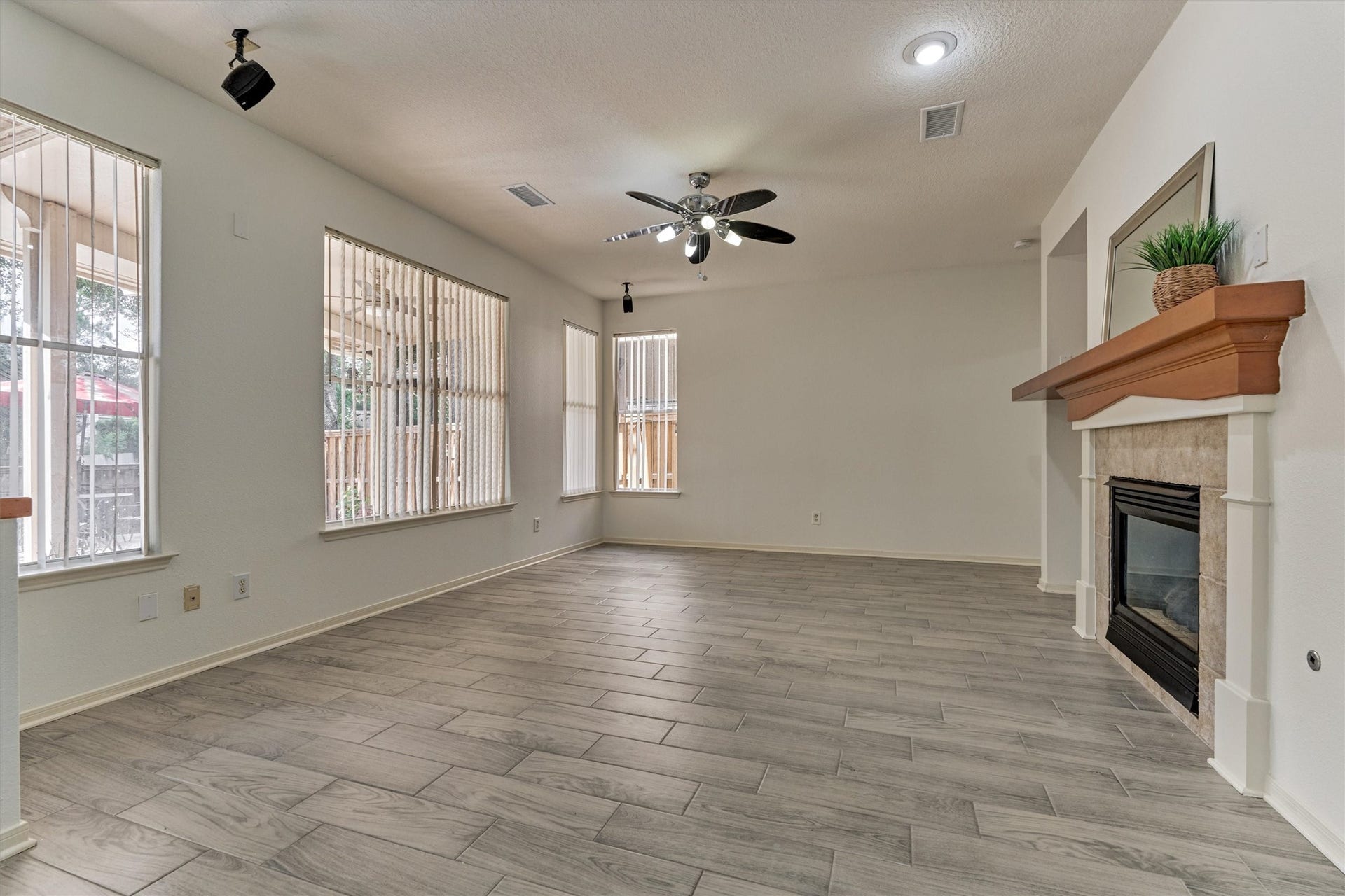 11 Vinca Trail, The Woodlands, TX 77382 the family room with gas fireplace and large windows offering views of the back yard with Pool and spa.