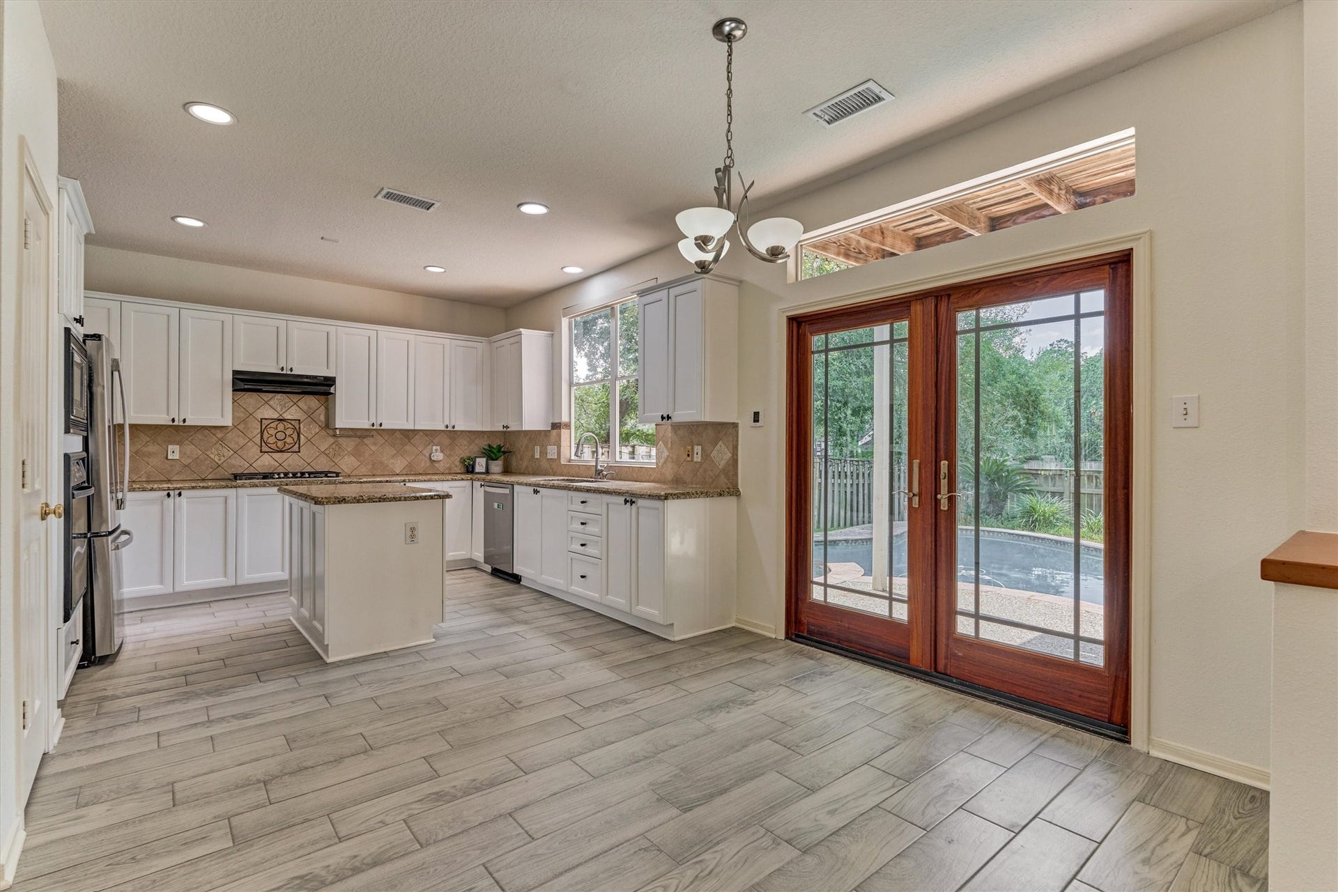 11 Vinca Trail, The Woodlands, TX 77382 The kitchen and breakfast dining area. The home has neutral tile flooring throughout the whole 1st floor.
