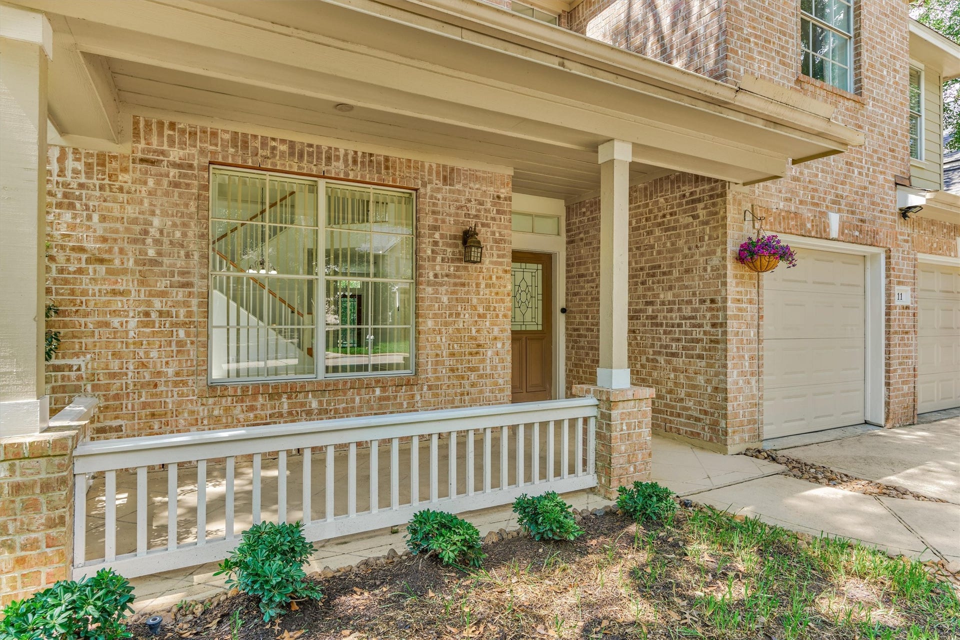 11 Vinca Trail, The Woodlands, TX 77382 The front covered patio on the home. The home has great curb appeal with a soft light brick exterior.