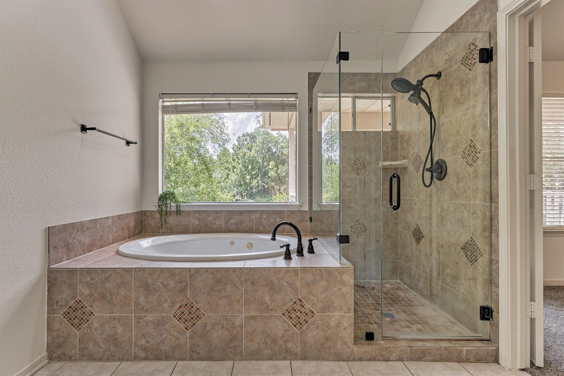 11 Vinca Trail, The Woodlands, TX 77382 The primary en suite has a large glass shower and soaker tub with treetop views.