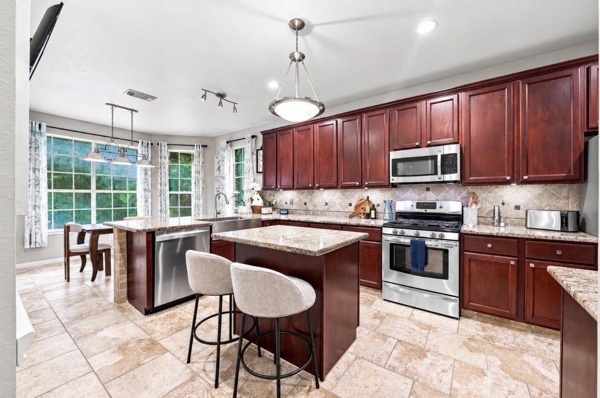 4118 Laurette Court, Sugar Land, TX 77479 Spacious kitchen with rich wooden cabinetry (cabinets have extra pull out storage), elegant granite countertops, and modern stainless steel appliances, featuring a cozy breakfast nook with large windows.