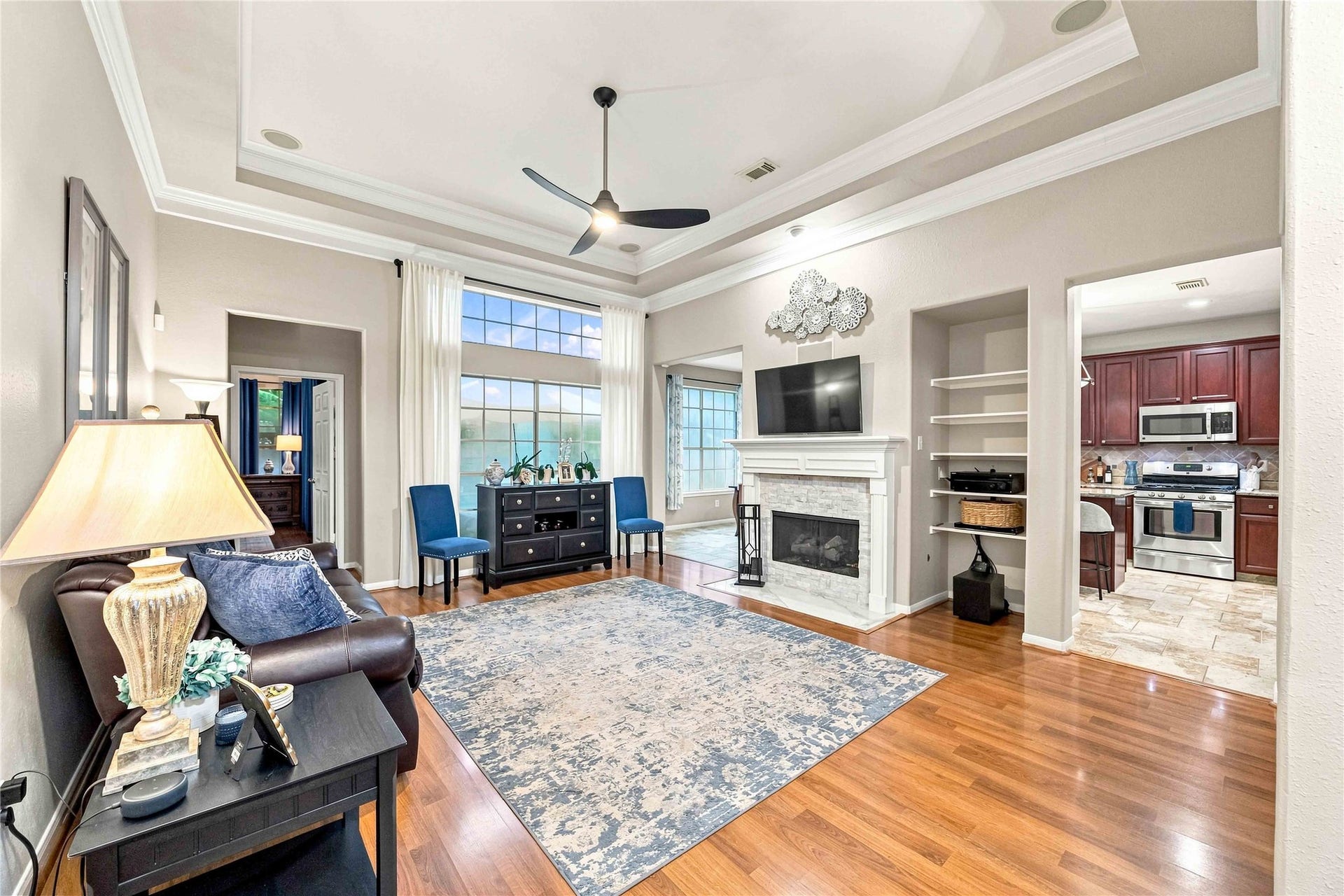 4118 Laurette Court, Sugar Land, TX 77479 Elegant living room with crown molding, a cozy fireplace, tray ceiling and abundant natural light, seamlessly connected to the timeless kitchen.