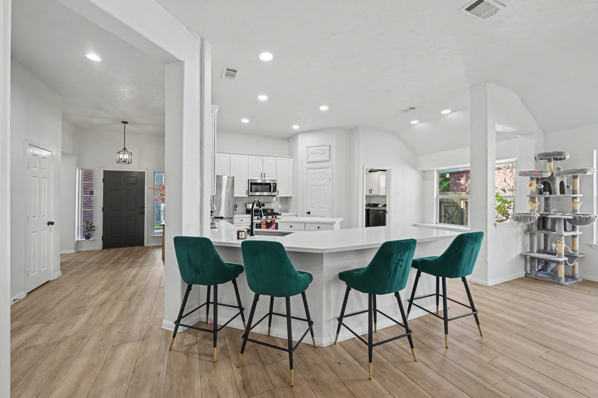 Spacious kitchen with white cabinetry, stainless steel appliances, and a large breakfast bar, perfect for casual dining or entertaining.