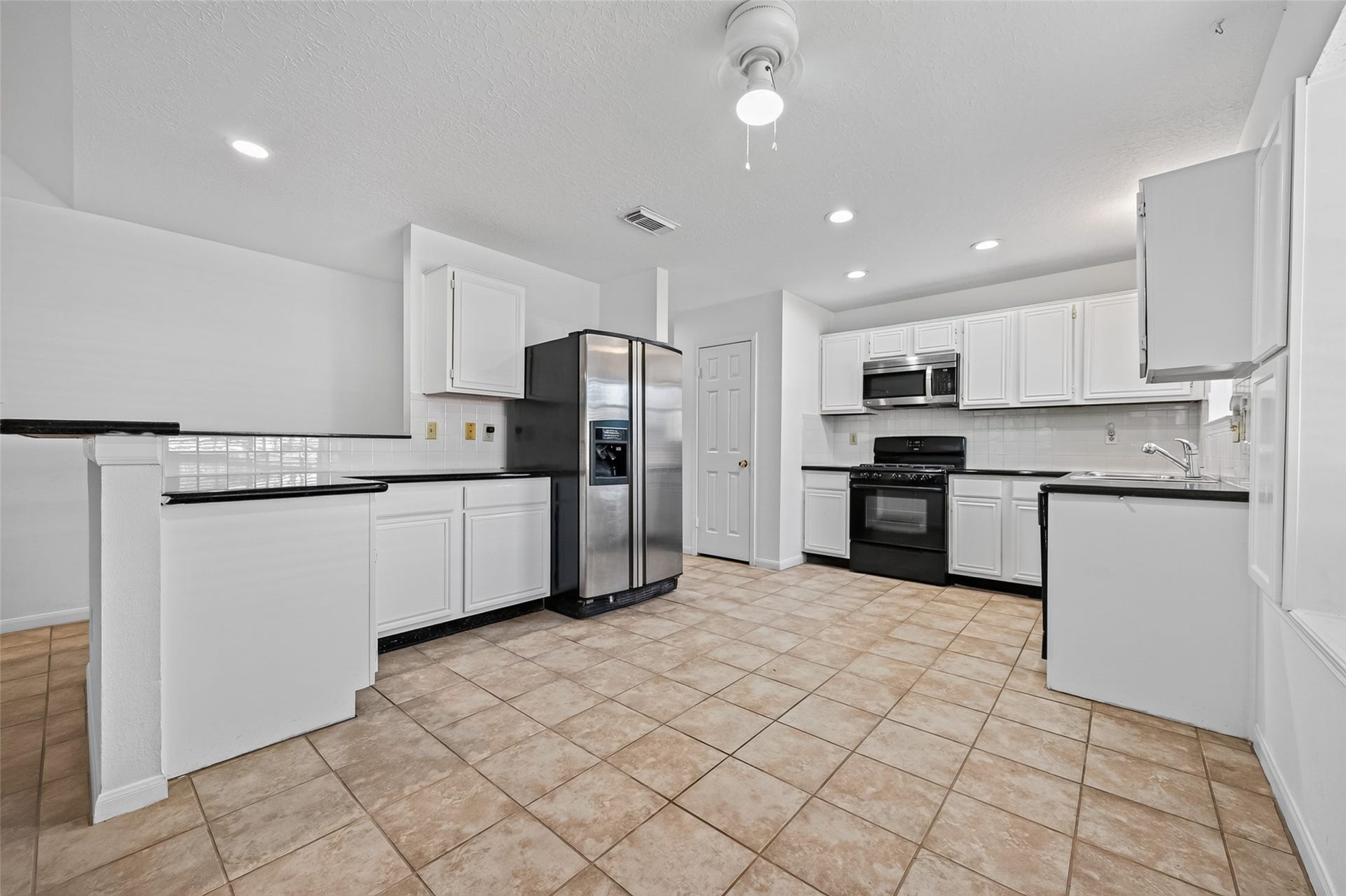 2703 Blue Mist Drive, Sugar Land, TX 77498 Spacious living area with plush carpeting, abundant natural light from large windows, and an elegant chandelier creating a warm and inviting atmosphere.