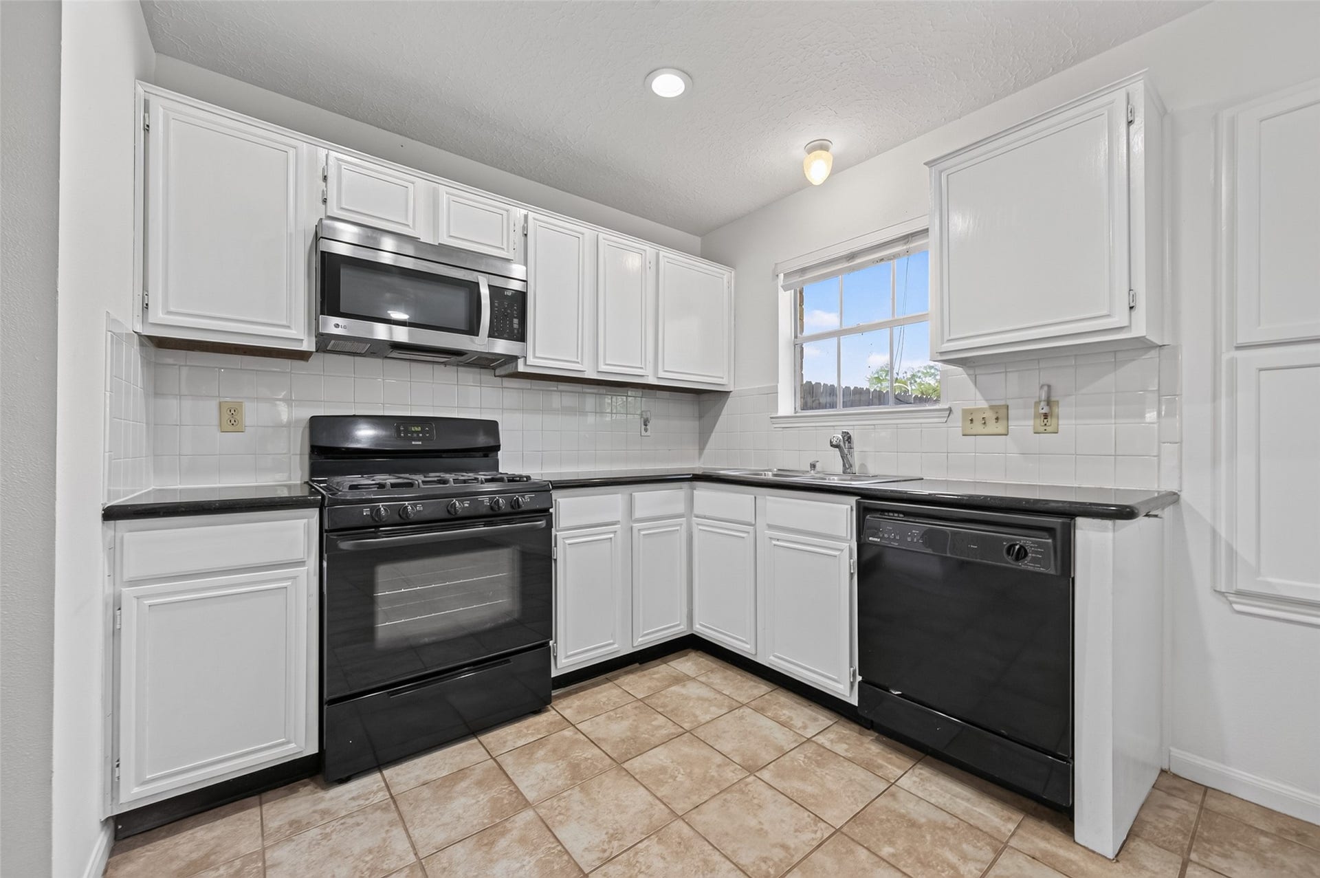 2703 Blue Mist Drive, Sugar Land, TX 77498 Spacious kitchen with modern stainless steel appliances, sleek white cabinetry, and a convenient tile floor, perfect for cooking and entertaining.