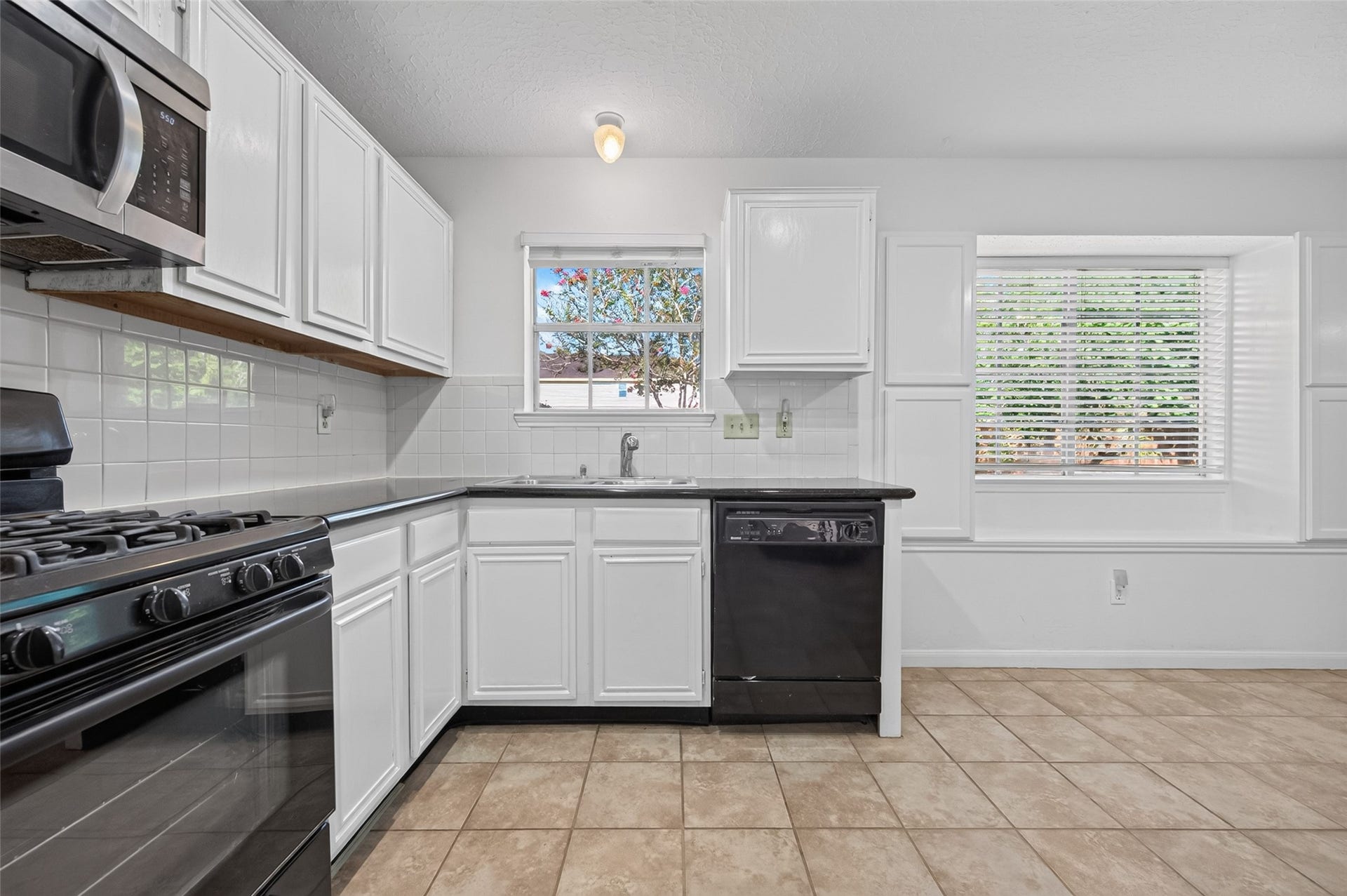 2703 Blue Mist Drive, Sugar Land, TX 77498 Bright and spacious kitchen featuring sleek black appliances, ample white cabinetry, and a large window that floods the area with natural light.