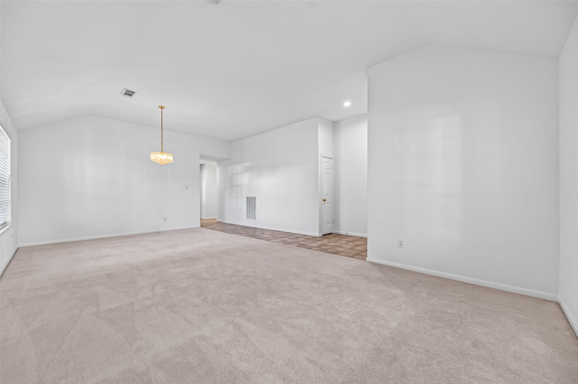 2703 Blue Mist Drive, Sugar Land, TX 77498 Spacious, light-filled living area with plush carpeting, elegant lighting fixture, and a seamless transition to tiled entryway.