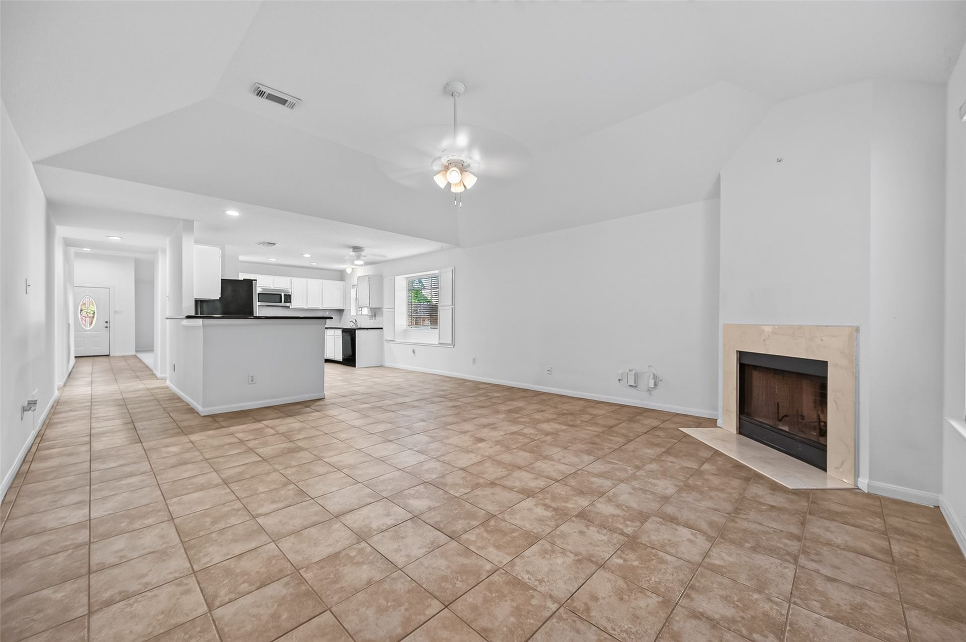 2703 Blue Mist Drive, Sugar Land, TX 77498 Spacious living area with a cozy corner fireplace, neutral tile flooring, and abundant natural light from large windows, perfect for gatherings and relaxation.