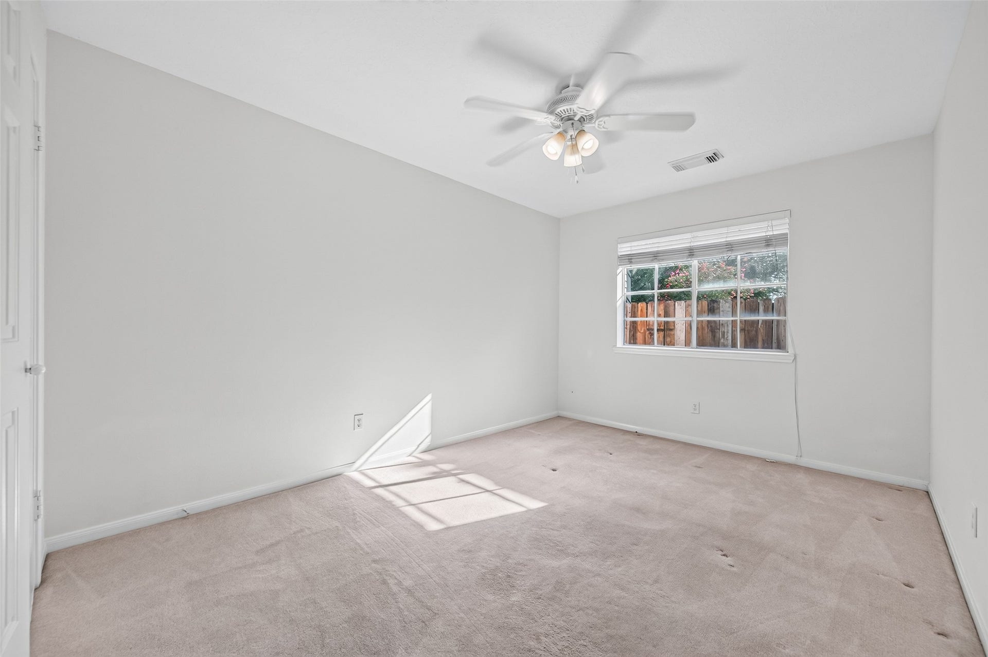 2703 Blue Mist Drive, Sugar Land, TX 77498 Bright and airy bedroom with neutral walls, plush carpeting, and a ceiling fan. A large window offers plenty of natural light and a view of the backyard.