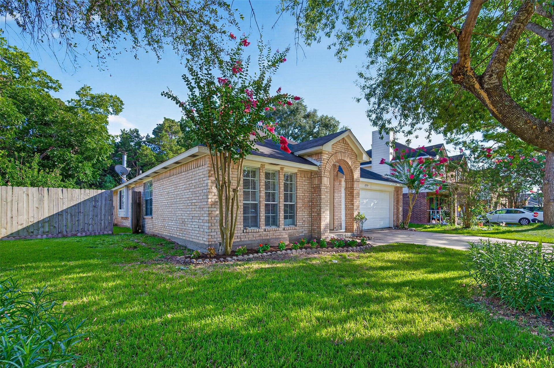 2703 Blue Mist Drive, Sugar Land, TX 77498 Charming single-story brick home with a manicured front yard, nestled under mature trees, offering a welcoming archway entrance and a spacious driveway.