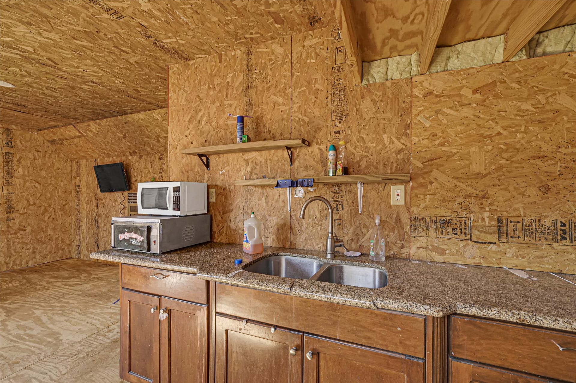 121 Patterson Road, Brazoria, TX 77422 Rustic kitchen space featuring wood paneling, granite countertops, a double sink, and open shelving for convenience.