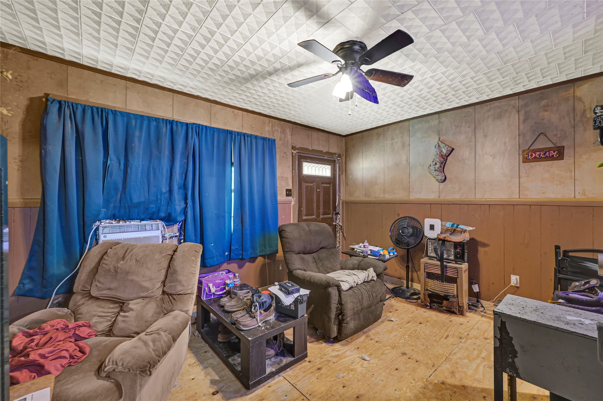 121 Patterson Road, Brazoria, TX 77422 Cozy living space featuring wood-paneled walls, a ceiling fan, and plush armchairs, offering a warm and inviting atmosphere.