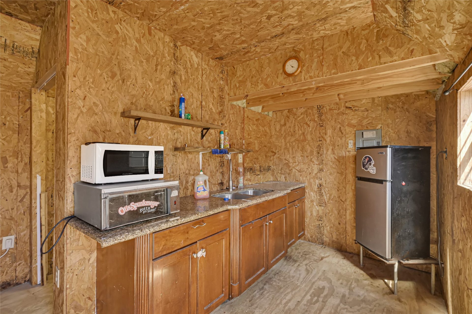 121 Patterson Road, Brazoria, TX 77422 Cozy kitchenette with rustic wood paneling, featuring a compact fridge, microwave, and countertop oven, offering functional space for meal prep.