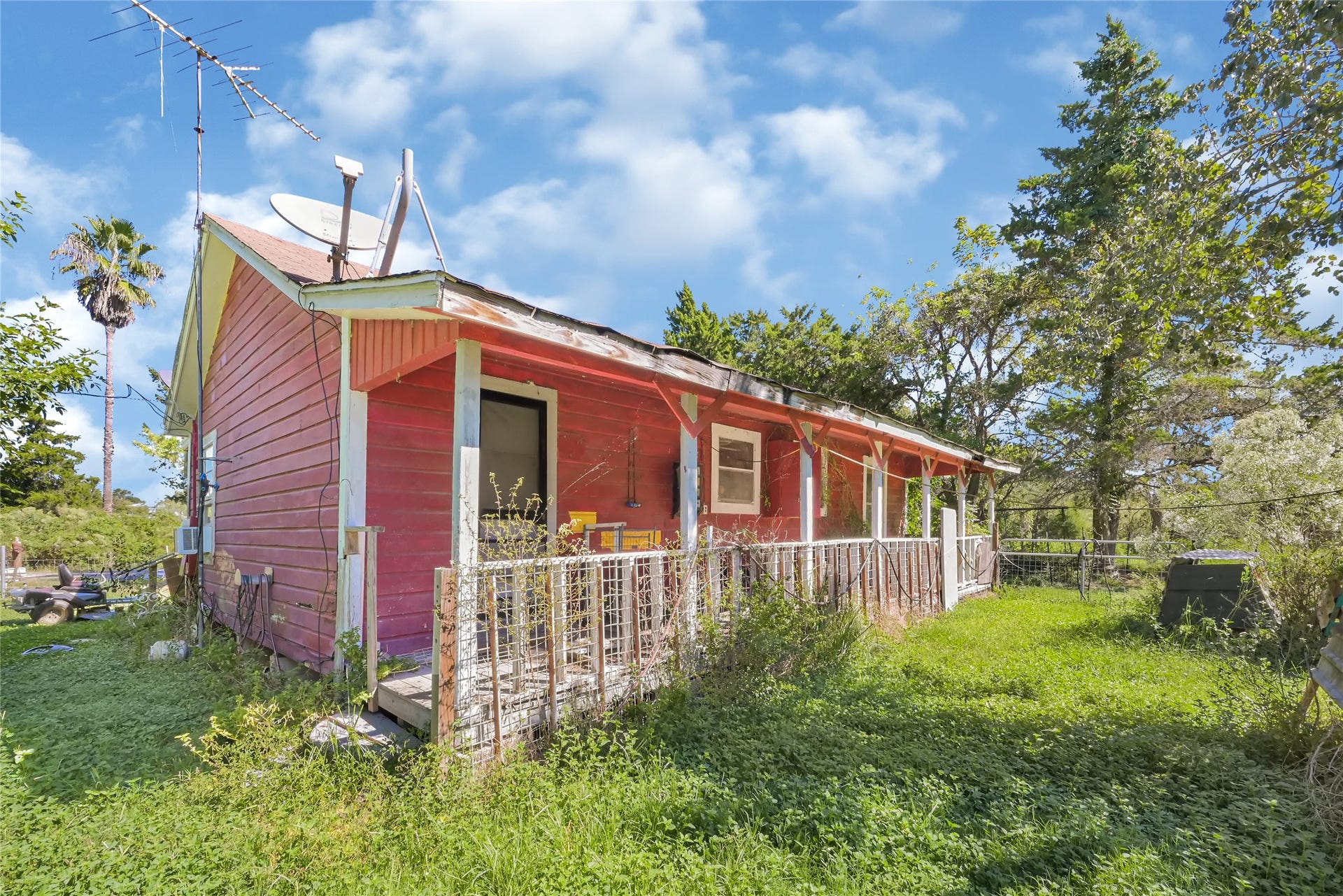 121 Patterson Road, Brazoria, TX 77422 Charming rustic home with a vibrant exterior, spacious porch, and surrounded by lush greenery, offering a serene retreat.