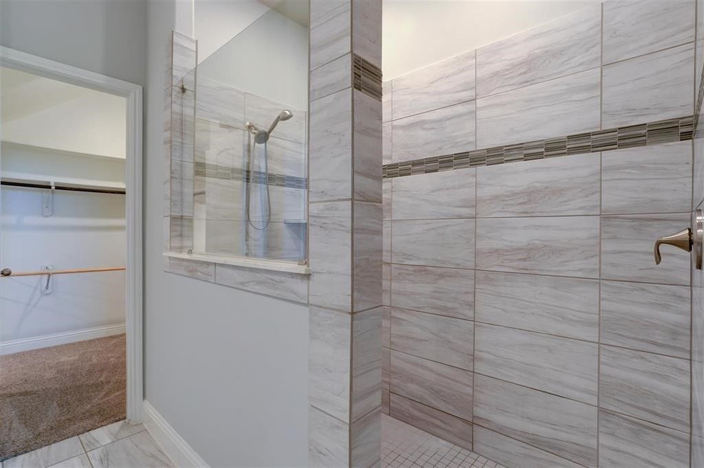 23715 Ruby Bramble Trail, Katy, TX 77493 Elegant walk-in shower with modern tile design and adjacent spacious walk-in closet.