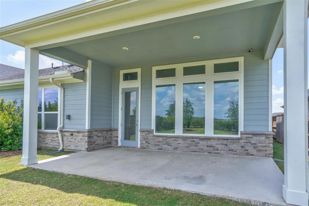 23715 Ruby Bramble Trail, Katy, TX 77493 Charming covered patio with elegant stone accents and expansive windows, offering a peaceful view and ample natural light.