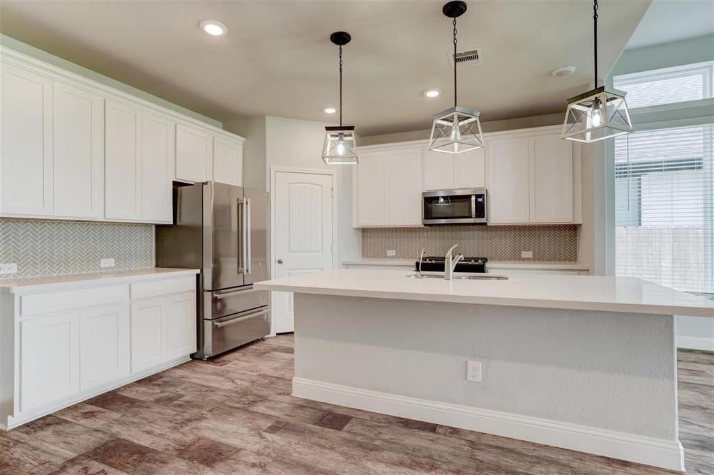23715 Ruby Bramble Trail, Katy, TX 77493 Modern kitchen featuring sleek white cabinetry, stainless steel appliances, and a spacious island with pendant lighting.
