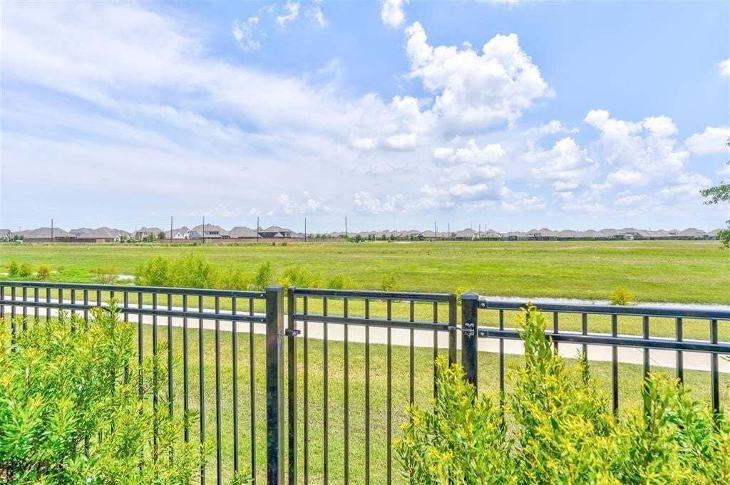 23715 Ruby Bramble Trail, Katy, TX 77493 Expansive views of a lush green landscape beyond a stylish metal fence, offering a serene and open atmosphere.