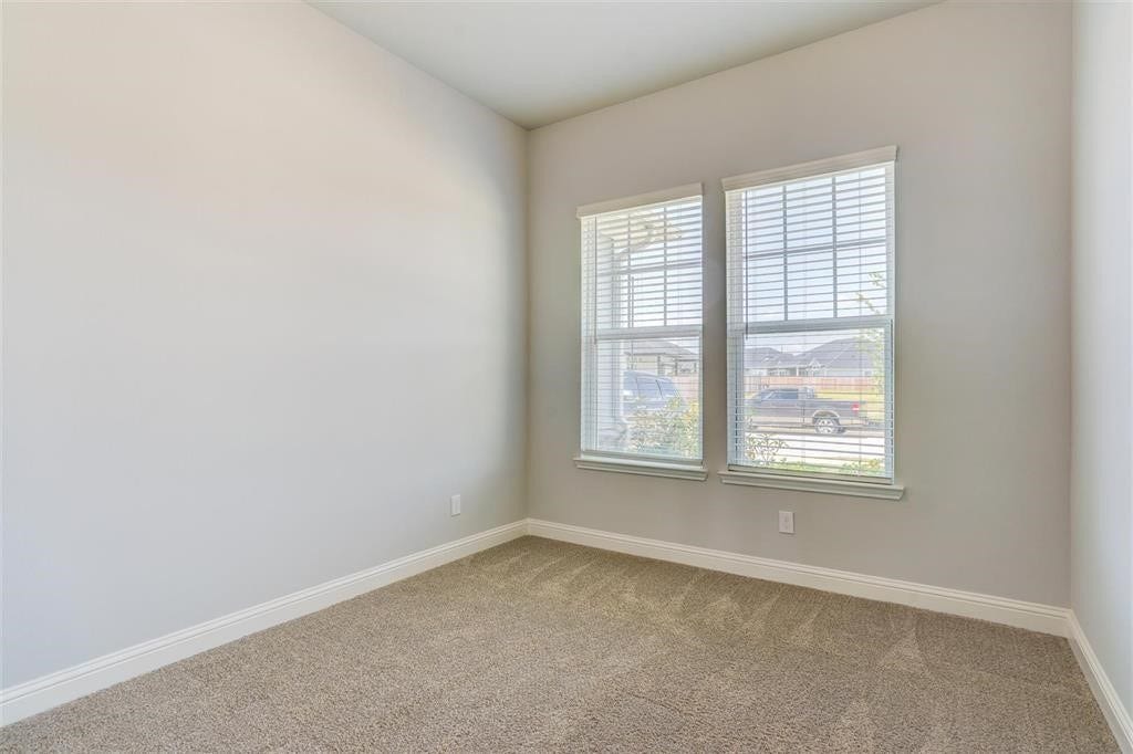23715 Ruby Bramble Trail, Katy, TX 77493 Bright and cozy secondary bedroom on the first floor with large windows, soft carpet, and neutral walls, perfect for a home office or small bedroom.