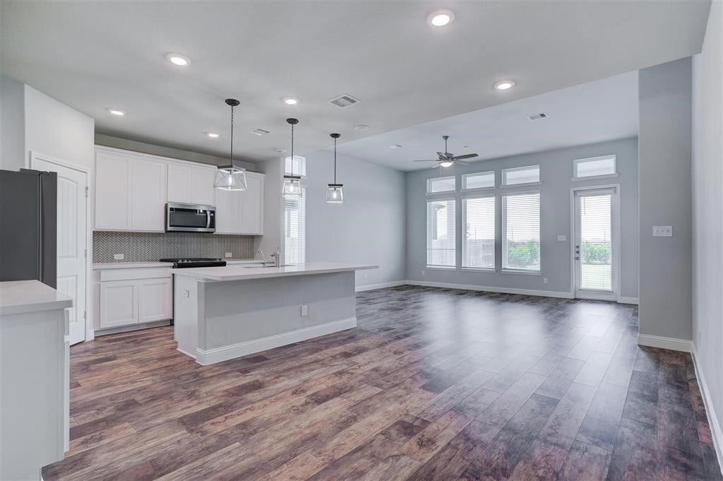 23715 Ruby Bramble Trail, Katy, TX 77493 Spacious open-concept living area featuring beautiful hardwood floors, a modern kitchen with a large island, and abundant natural light from large windows and glass doors.
