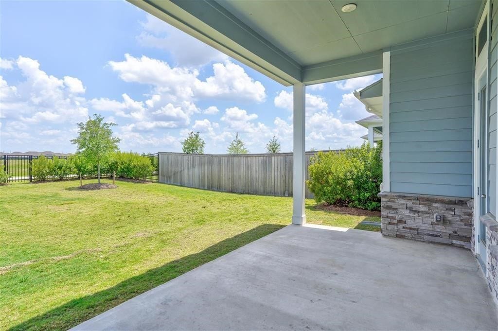 23715 Ruby Bramble Trail, Katy, TX 77493 Spacious covered patio overlooks a lush, fenced backyard, perfect for relaxing or entertaining with serene views of the open sky.