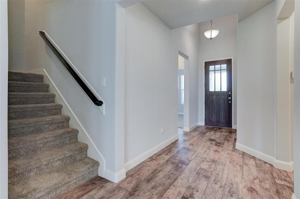 23715 Ruby Bramble Trail, Katy, TX 77493 Inviting entryway featuring elegant wood flooring, a stylish dark wood front door, and a carpeted staircase leading to the upper level.