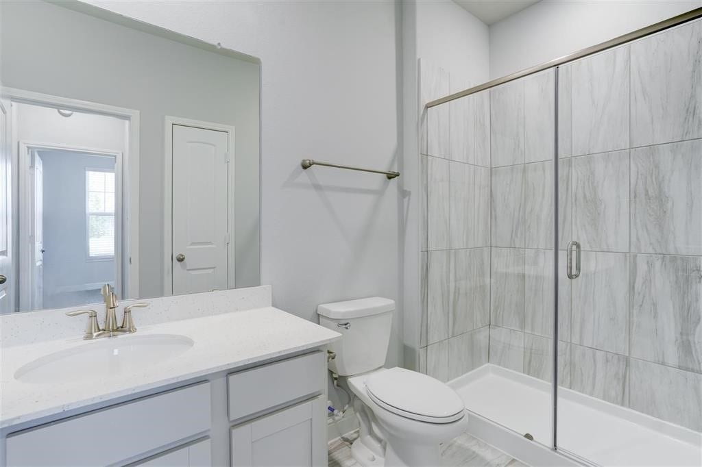 23715 Ruby Bramble Trail, Katy, TX 77493 Bright and modern secondary bathroom featuring a sleek glass-enclosed shower, elegant marble tile, and a spacious vanity with a quartz countertop.