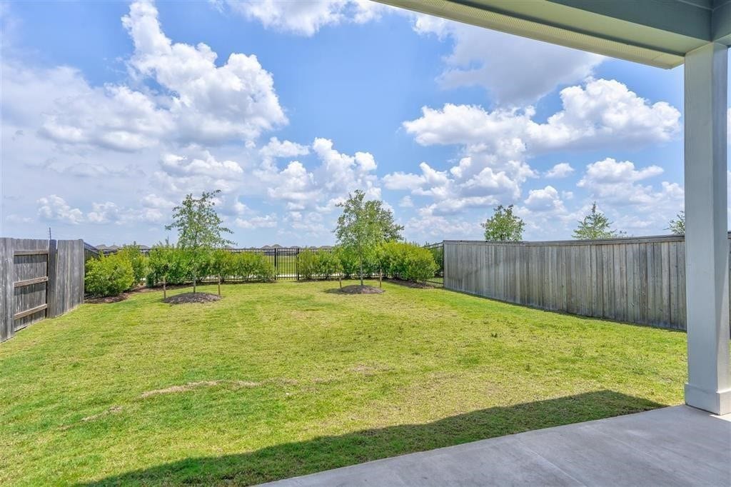 23715 Ruby Bramble Trail, Katy, TX 77493 Spacious backyard with lush green lawn, bordered by a wooden fence and landscaped with young trees, perfect for outdoor activities and relaxation.