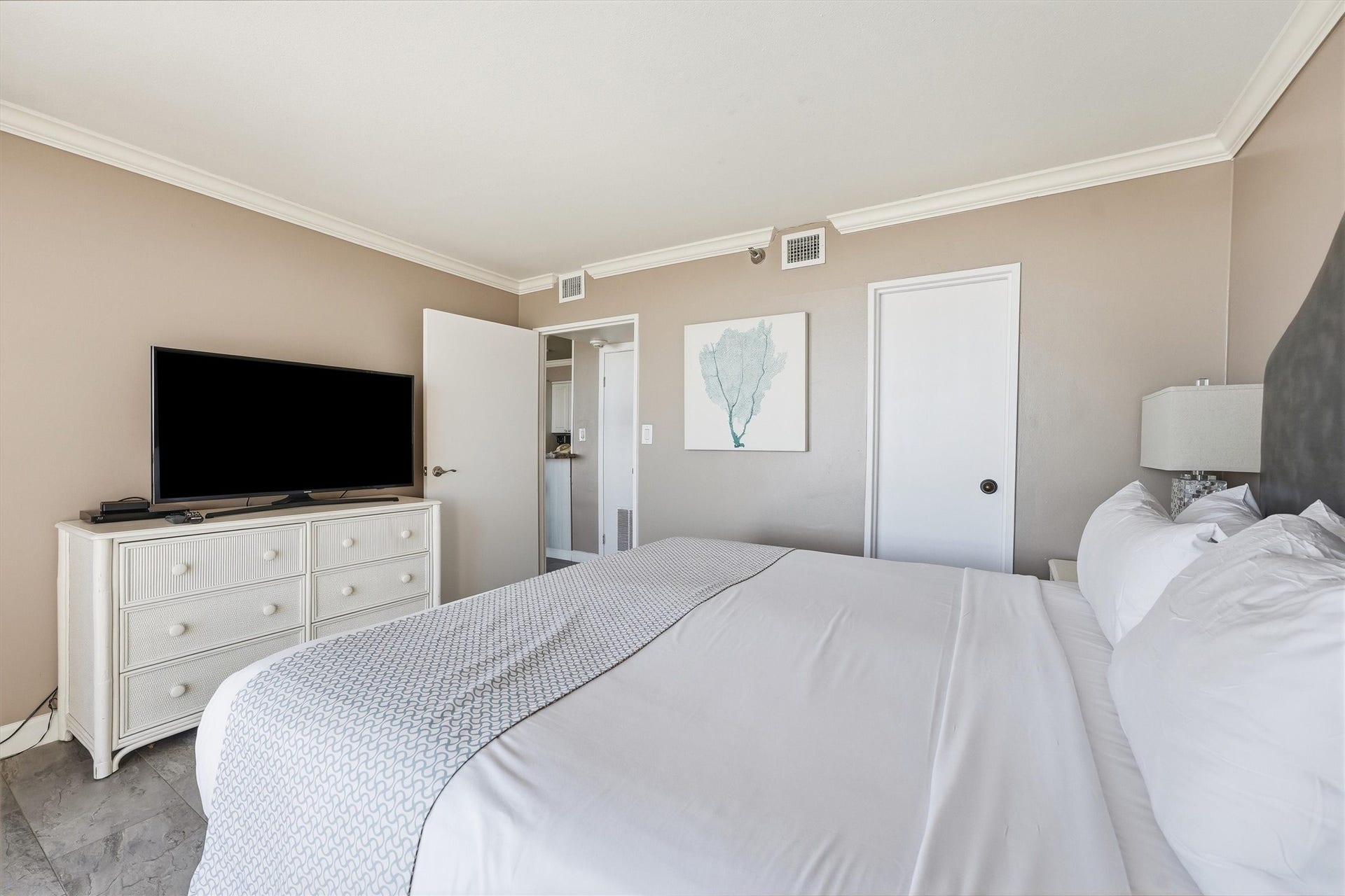 5220 Seawall Boulevard, #1233D, Galveston, TX 77551 Soft neutral tones, crown molding, and tile flooring create a restful bedroom retreat after a day at the beach.