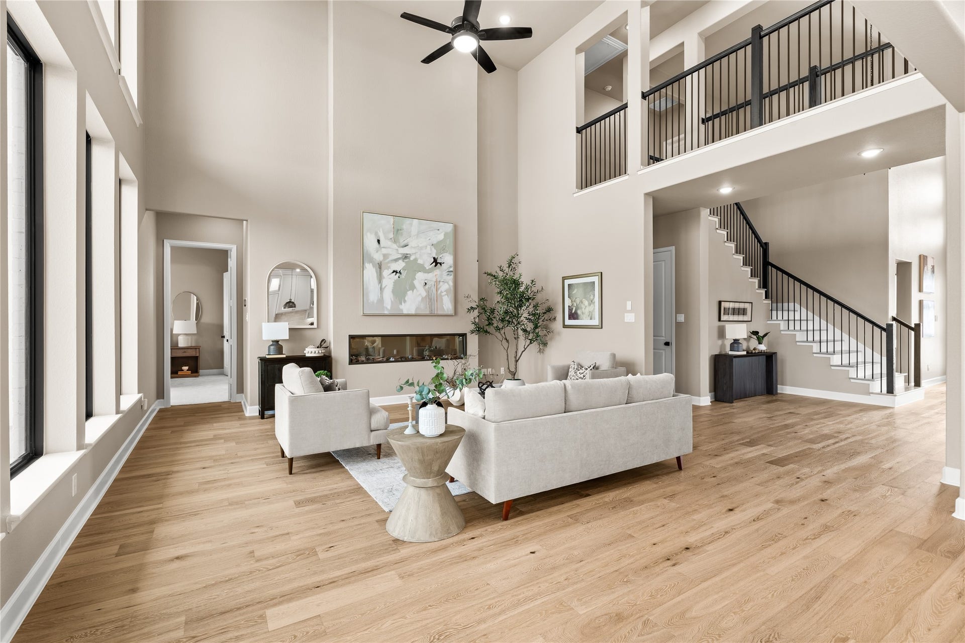 9607 Maple Wood Drive, Missouri City, TX 77459 Expansive living area with soaring ceilings, elegant hardwood floors, and a modern fireplace, complemented by a stylish open staircase and abundant natural light. *Virtually Staged*