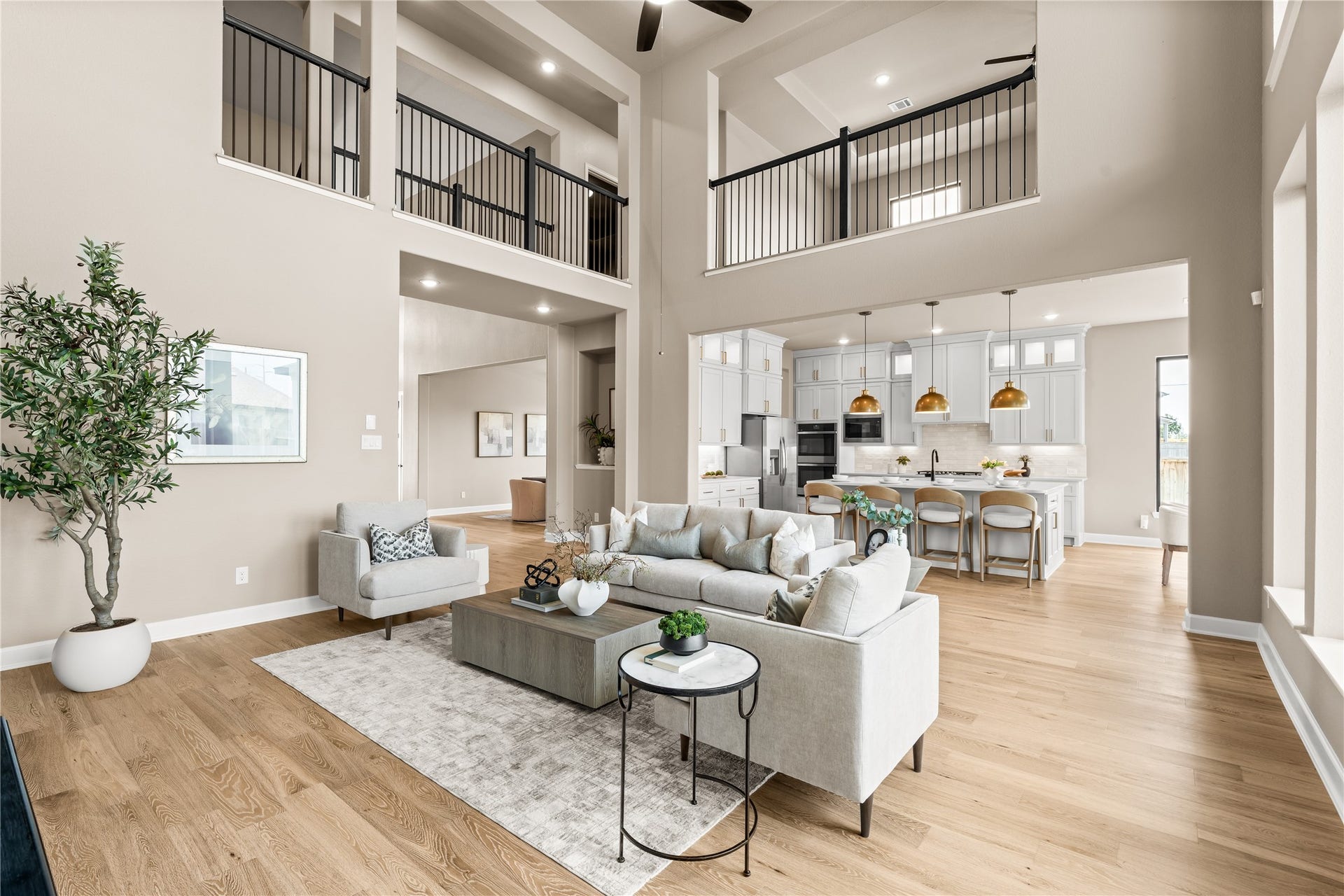 9607 Maple Wood Drive, Missouri City, TX 77459 Spacious open-concept living area featuring high ceilings, elegant wood flooring, and a modern kitchen with sleek white cabinetry and stylish pendant lighting. *Virtually Staged*