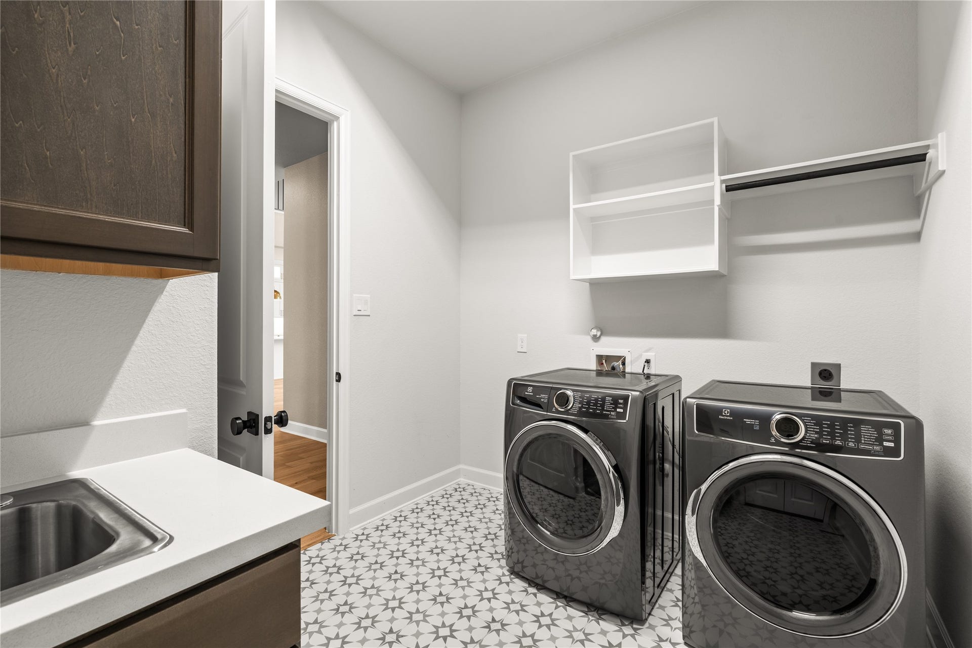 9607 Maple Wood Drive, Missouri City, TX 77459 Modern laundry room featuring sleek appliances, patterned tile flooring, and ample storage with cabinets and shelving.