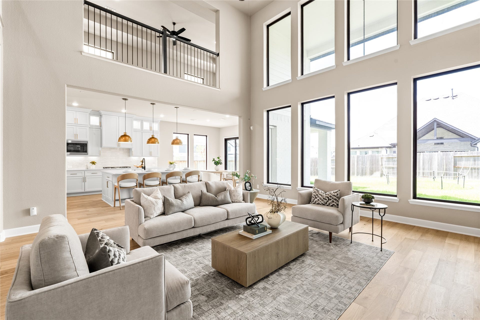 9607 Maple Wood Drive, Missouri City, TX 77459 Stunning open-concept living area with soaring ceilings, abundant natural light from floor-to-ceiling windows, and a modern kitchen featuring an island and elegant pendant lighting. *Virtually Staged*