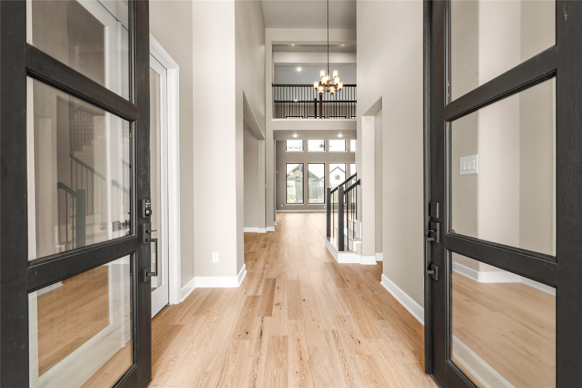 9607 Maple Wood Drive, Missouri City, TX 77459 Elegant entryway with high ceilings, abundant natural light, and a view through to the spacious open living area, highlighted by a modern chandelier and sleek staircase.