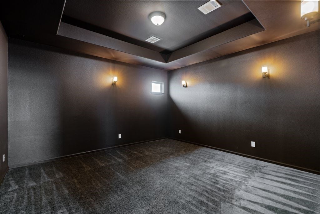9607 Maple Wood Drive, Missouri City, TX 77459 A modern media room outfitted with dark walls and ceiling, complemented by soft wall lighting creating an ideal ambiance for entertainment.